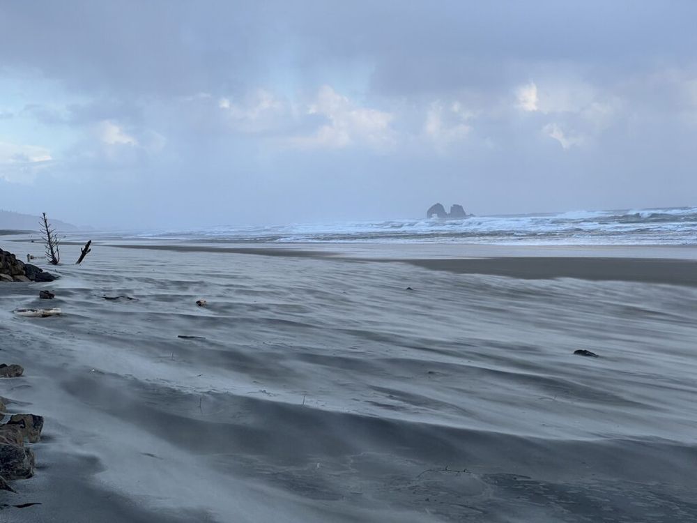 Wind-blown sand on a Rockaway Beach shoreline with Twin Rocks offshore